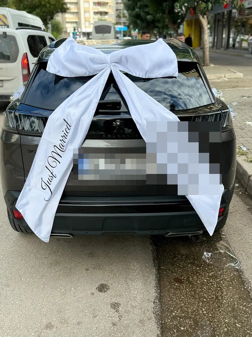 Koyu gri Peugeot aracın arka camında beyaz büyük fiyonk ve kurdeleler