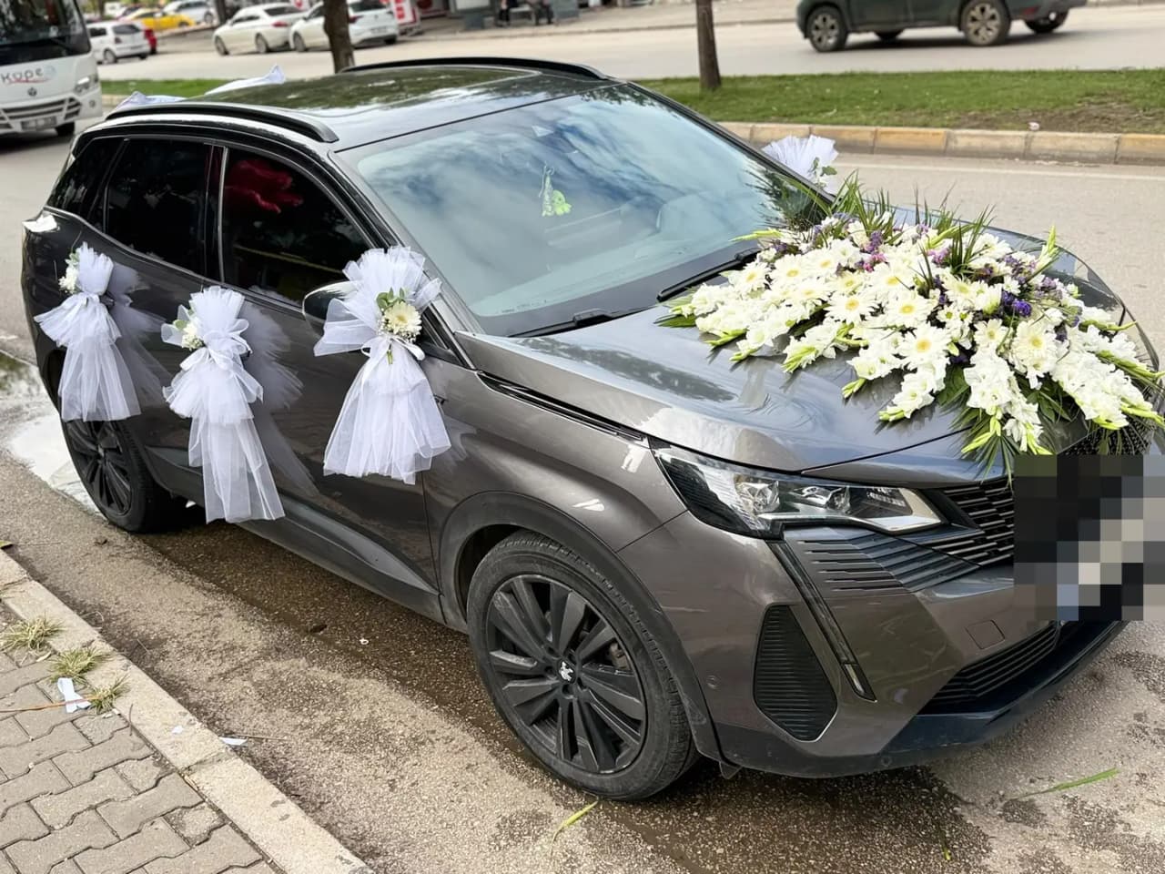 Gri Peugeot aracın kapılarında beyaz tül fiyonklar ve kaputta çiçek aranjmanı