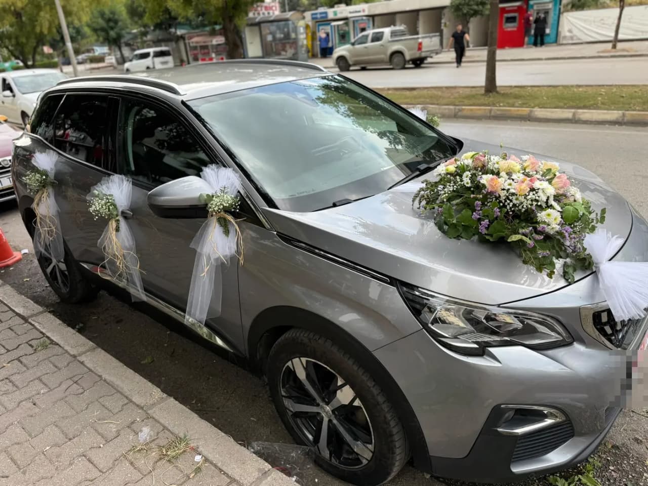Gri Peugeot aracın yan kapılarında tül fiyonklar ve kaputta beyaz çiçek buketi