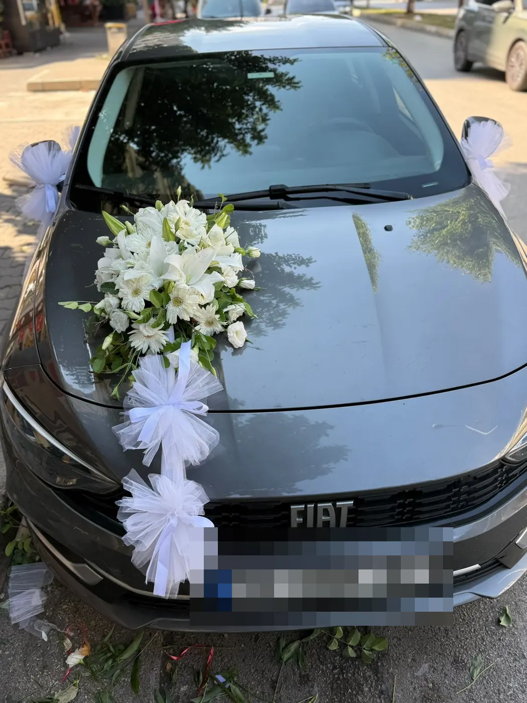 Gri Fiat aracın kaputunda beyaz çiçek süslemesi ve tül fiyonklar