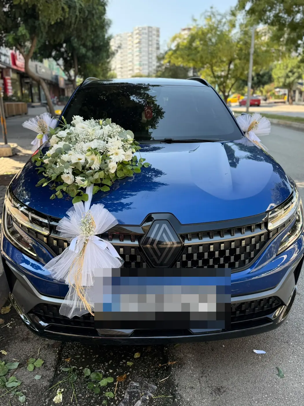 Mavi Renault aracın kaputunda beyaz çiçek buketi ve tül fiyonk