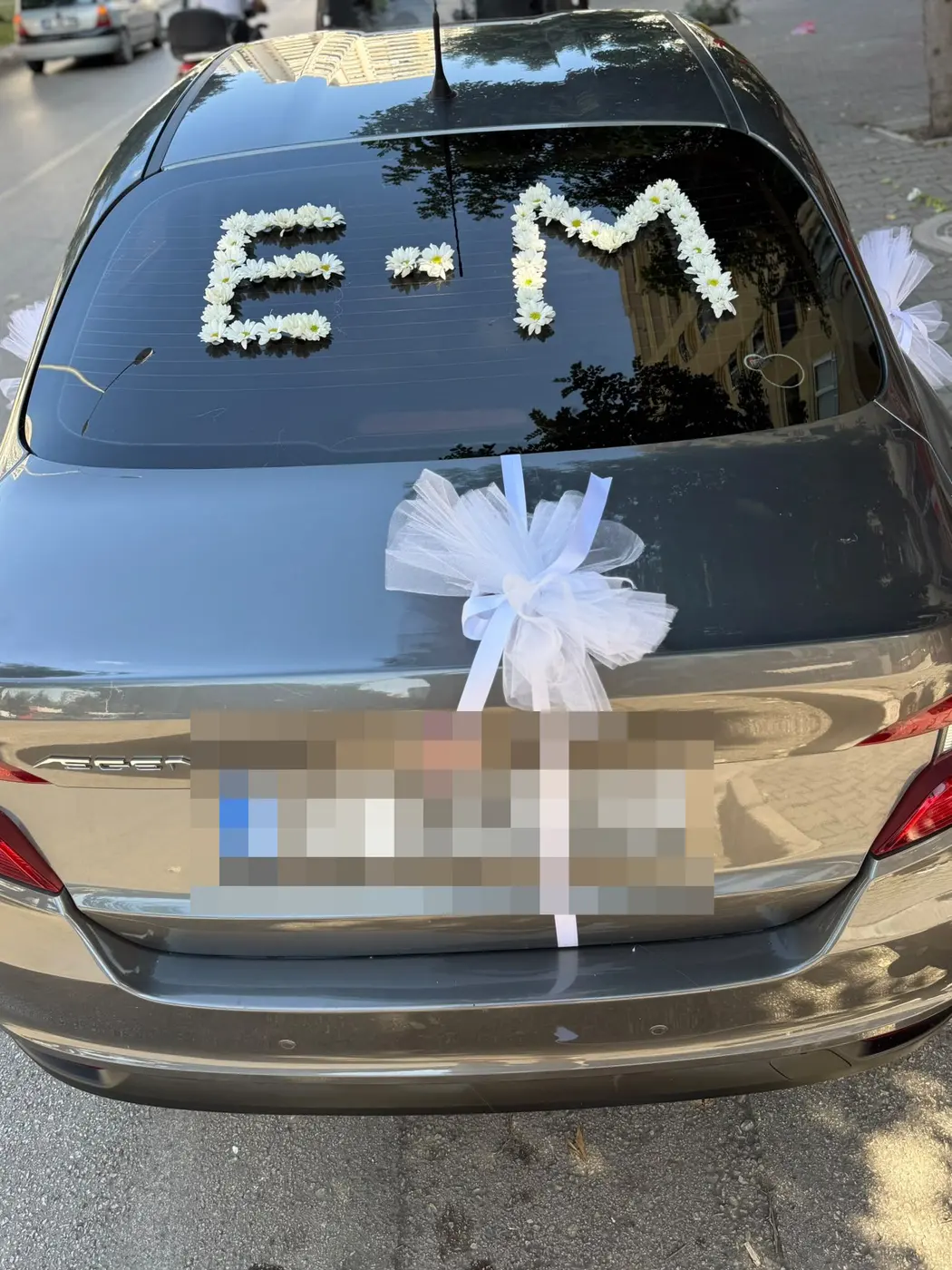 Bronz Fiat aracın arka camında beyaz çiçek harfleri ve bagajında tül fiyonk