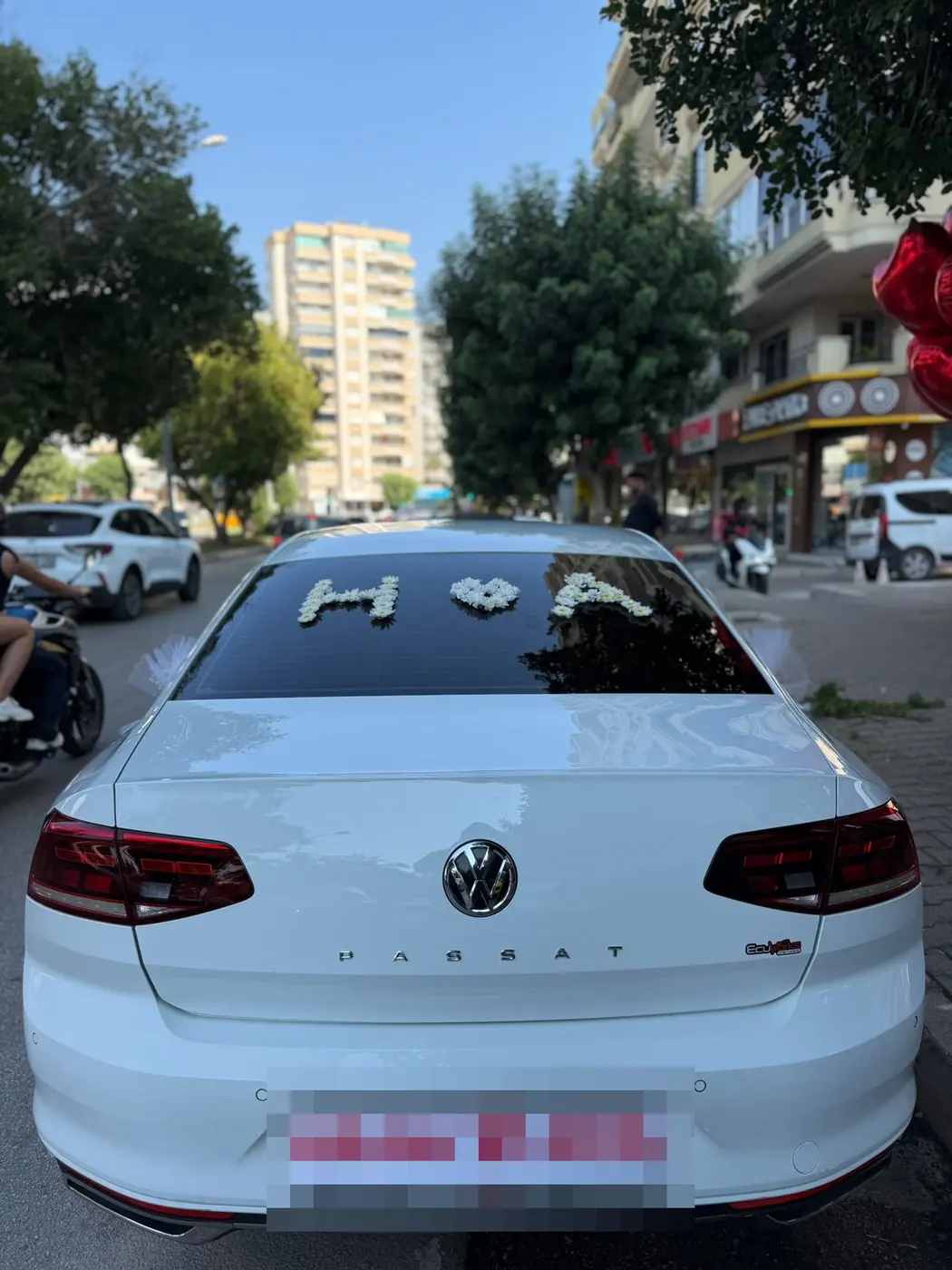 Beyaz VW aracın arka camında beyaz çiçek harfleri ve tabela