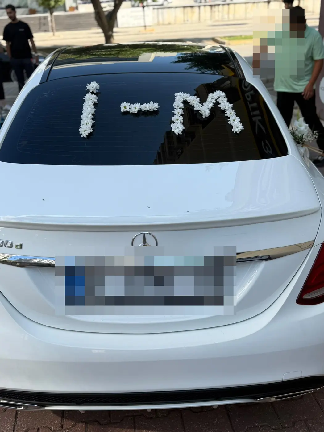 Beyaz Mercedes aracın arka camında beyaz çiçek harfleri
