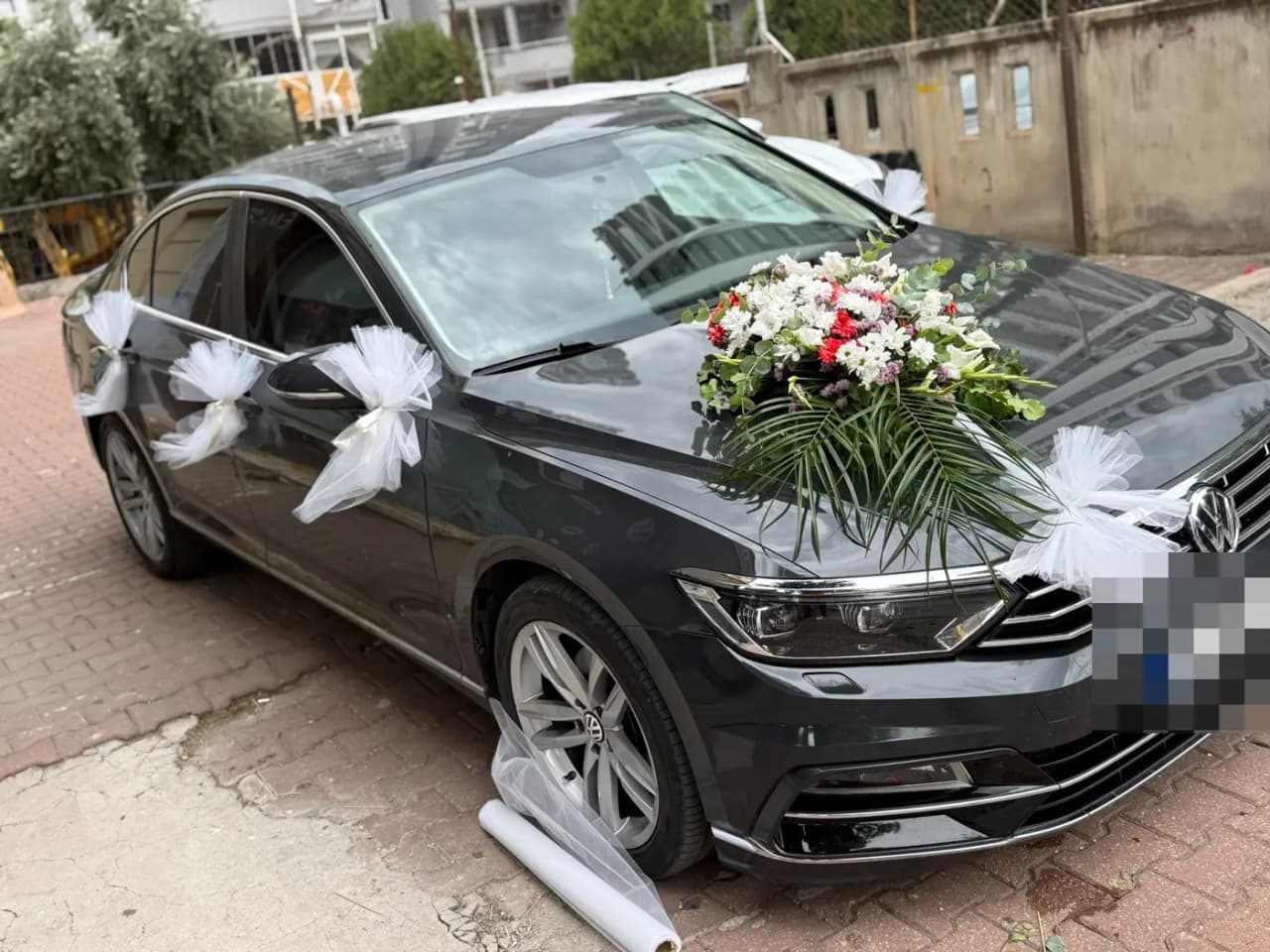 Koyu gri VW aracın kapılarında beyaz tül fiyonklar ve kaputta çiçek buketi