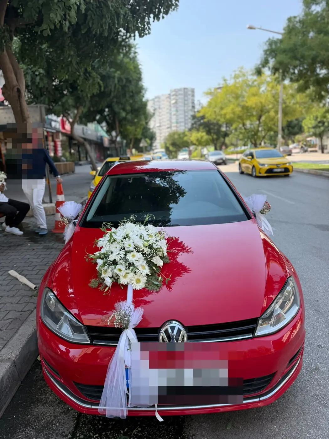 Kırmızı VW aracın ön kısmında beyaz tül fiyonk ve çiçek süslemesi