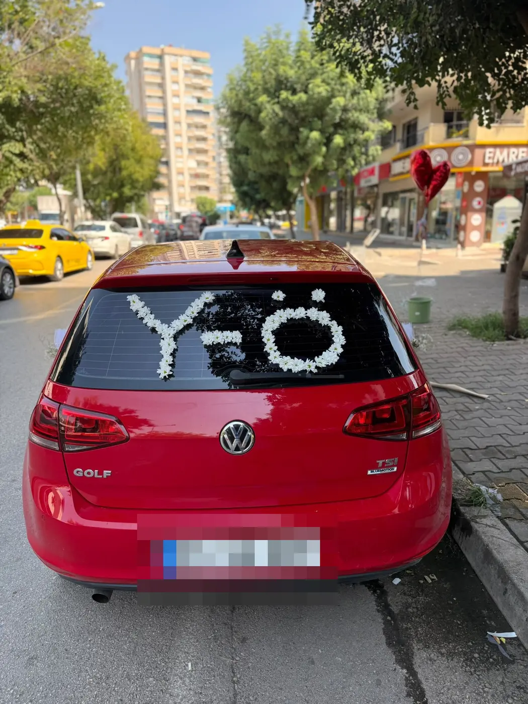 Kırmızı VW Golf aracın arka camında beyaz çiçek harfleri